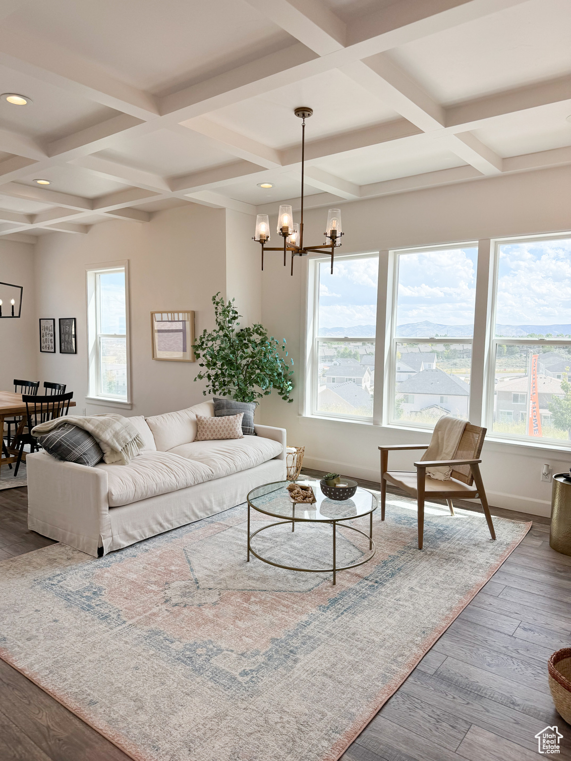 Living room featuring coffered ceiling, hardwood / wood-style floors, plenty of natural light, and a chandelier