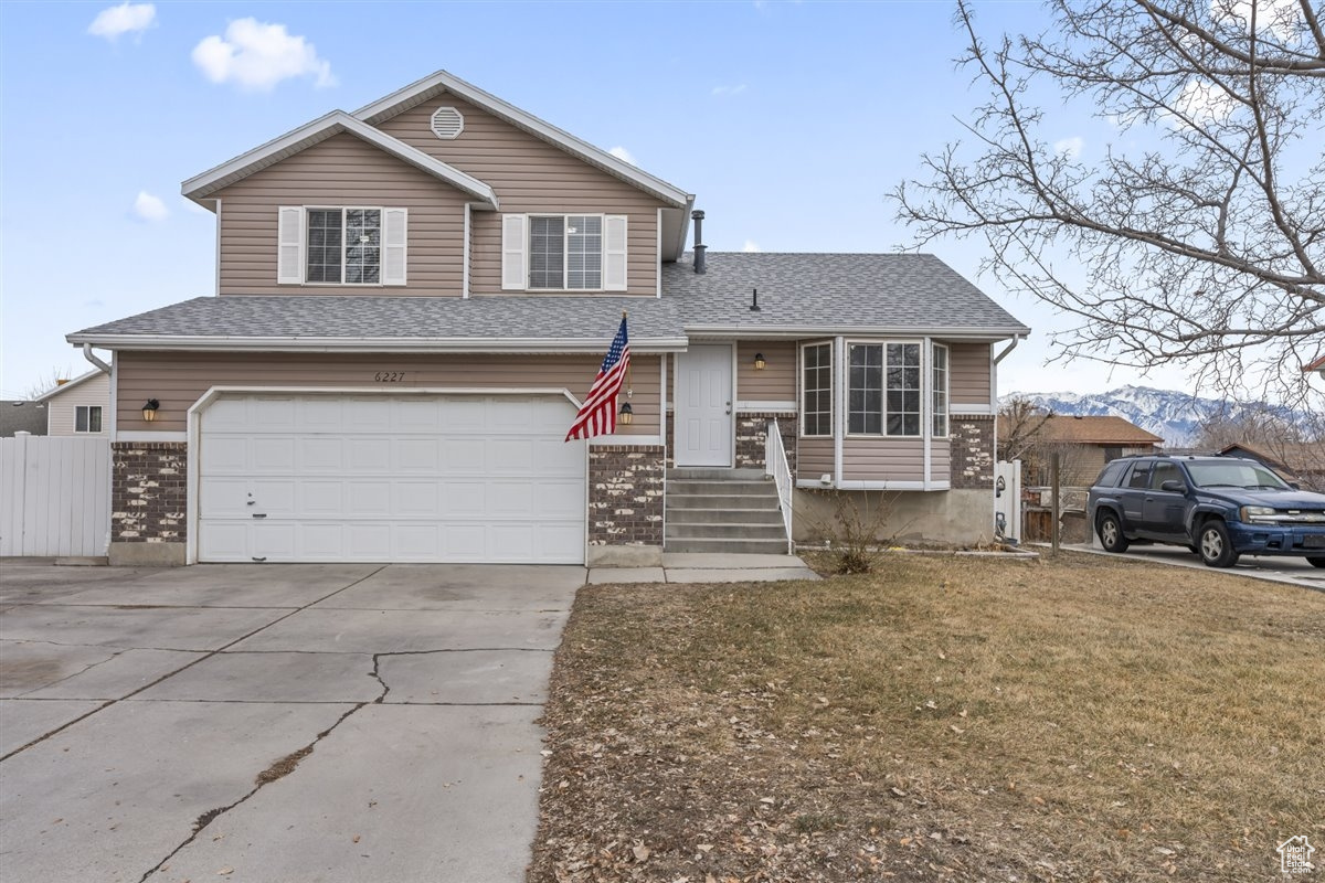 Tri-level home featuring a mountain view, a garage, and a front lawn