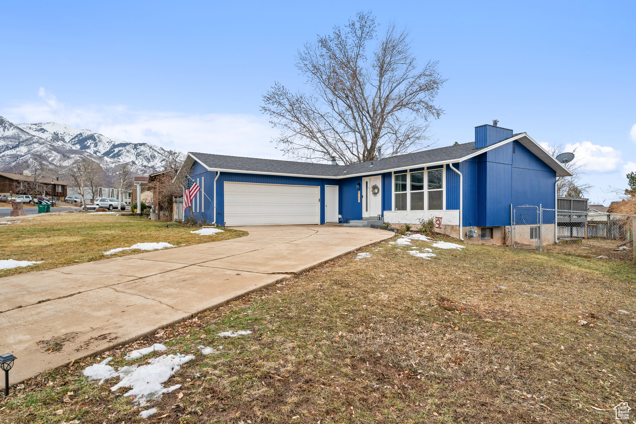 Ranch-style home featuring a garage, a mountain view, and a front lawn.