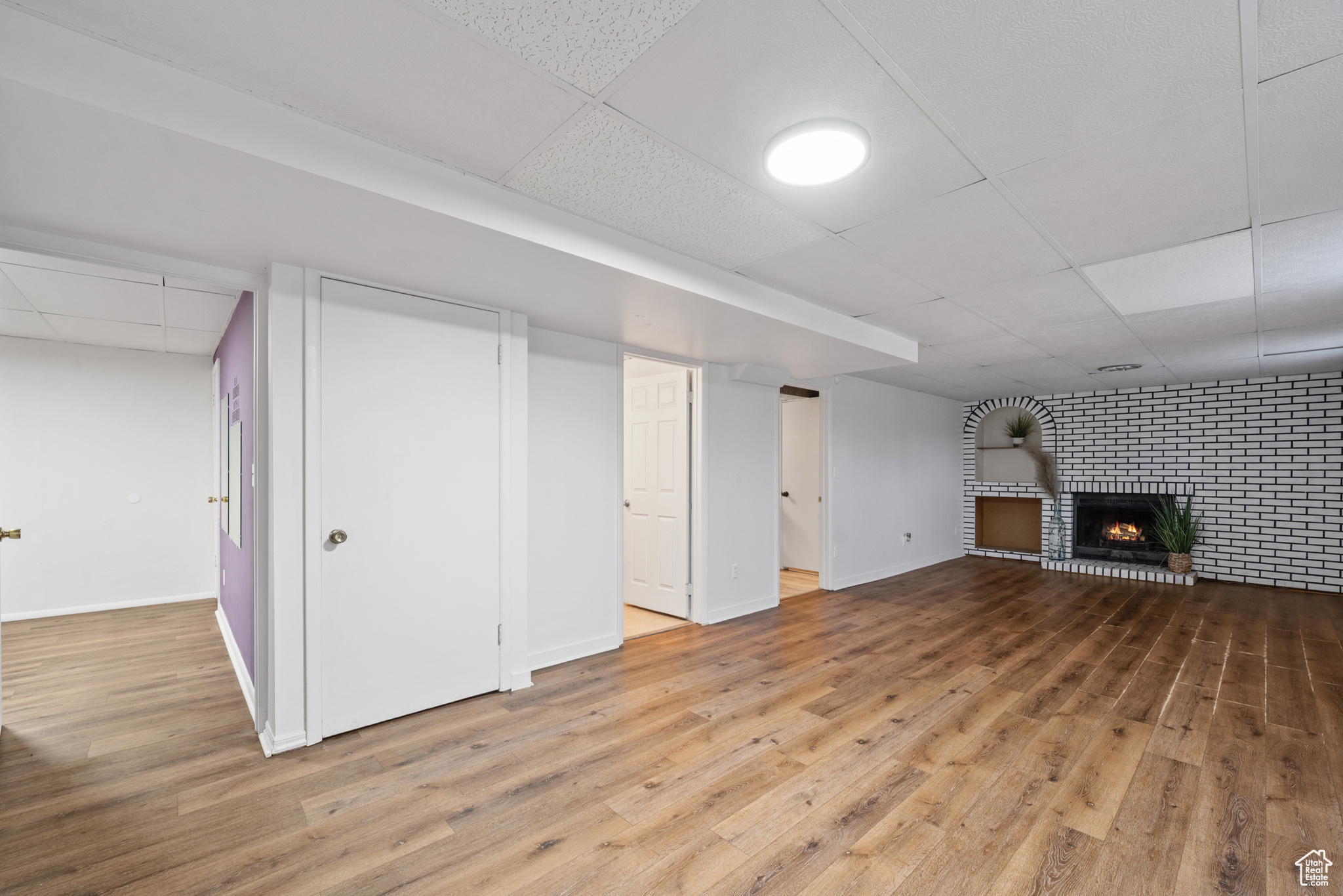 Basement with hardwood / wood-style flooring and brick fireplace.