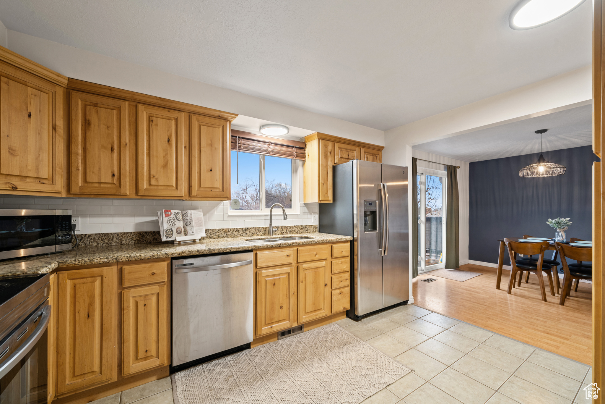 Kitchen featuring appliances with stainless steel finishes, sink, backsplash, and decorative light fixtures