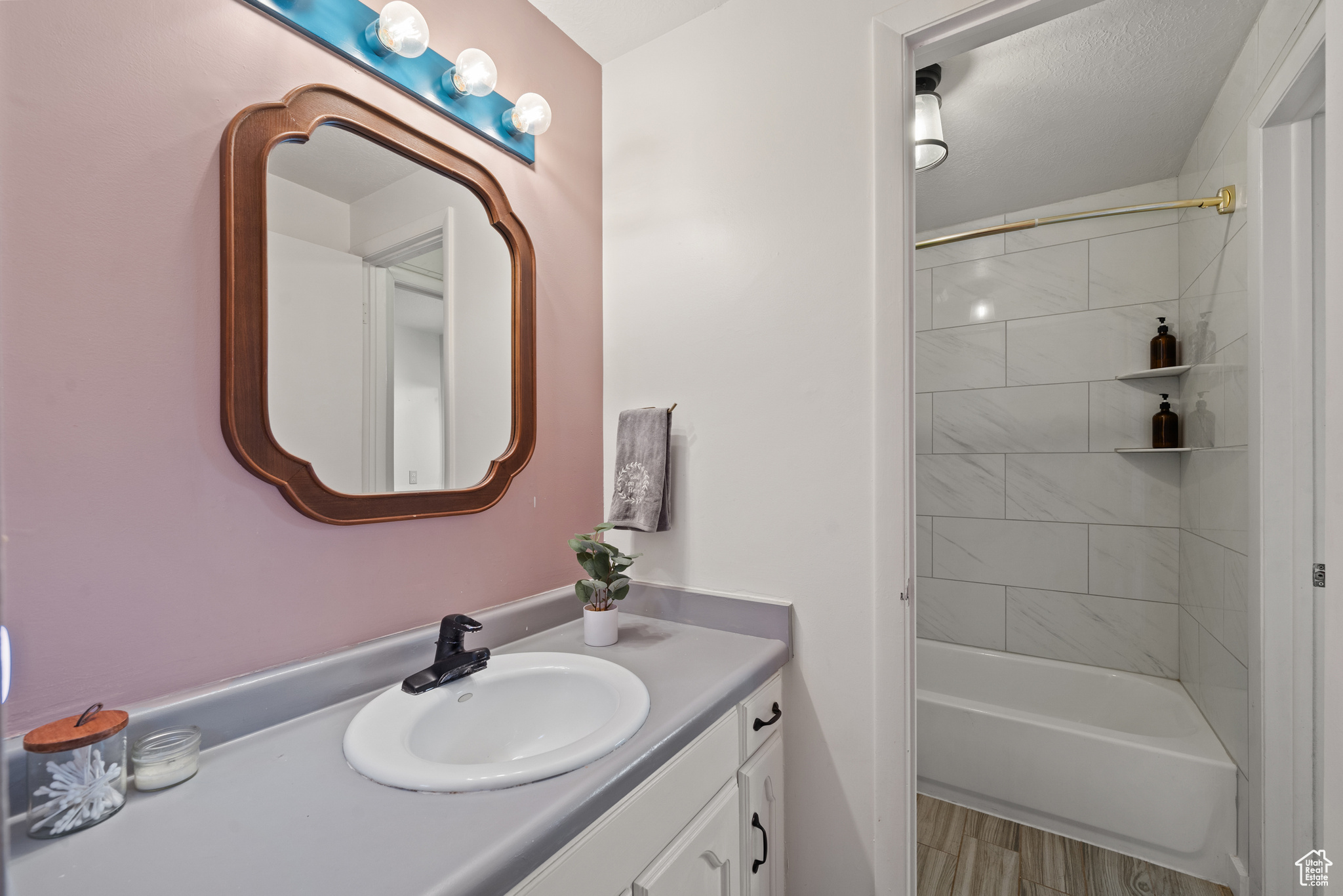 Newly remodeled bathroom - featuring vanity, tiled shower / bath combo, and wood-type flooring.