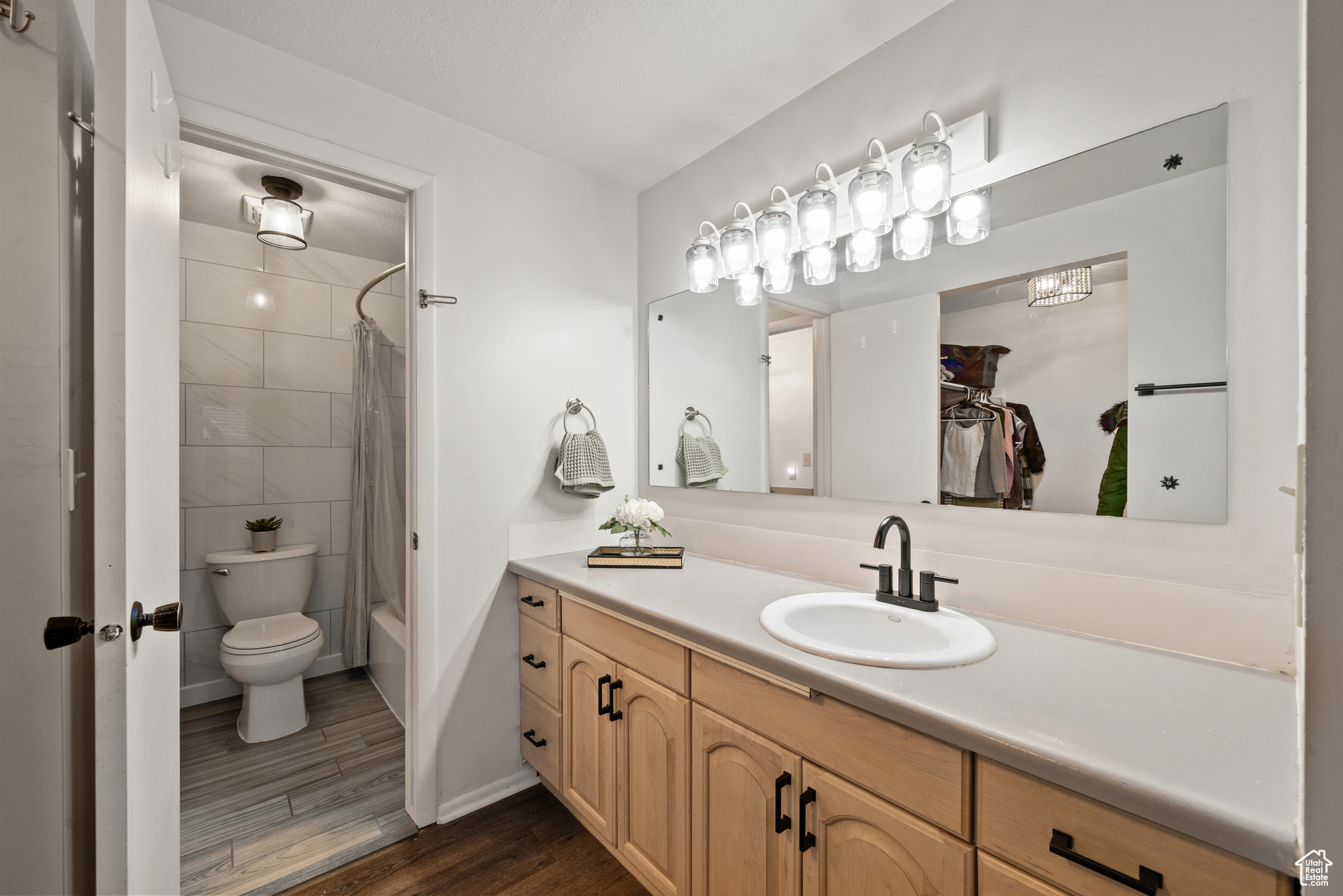 Full bathroom featuring vanity, wood-style floors, remolded shower / bath combination with curtain, and toilet