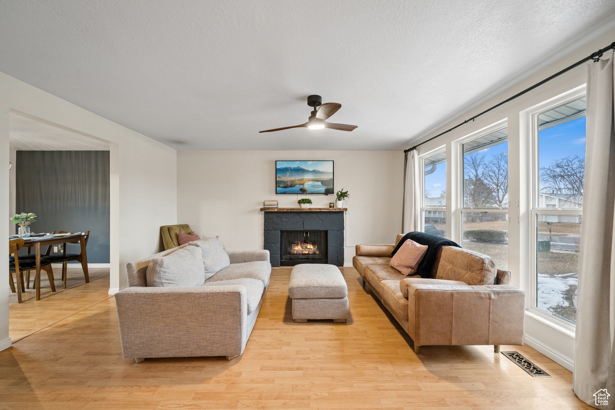 Living room with a tiled fireplace, a wealth of natural light, and light wood-type flooring