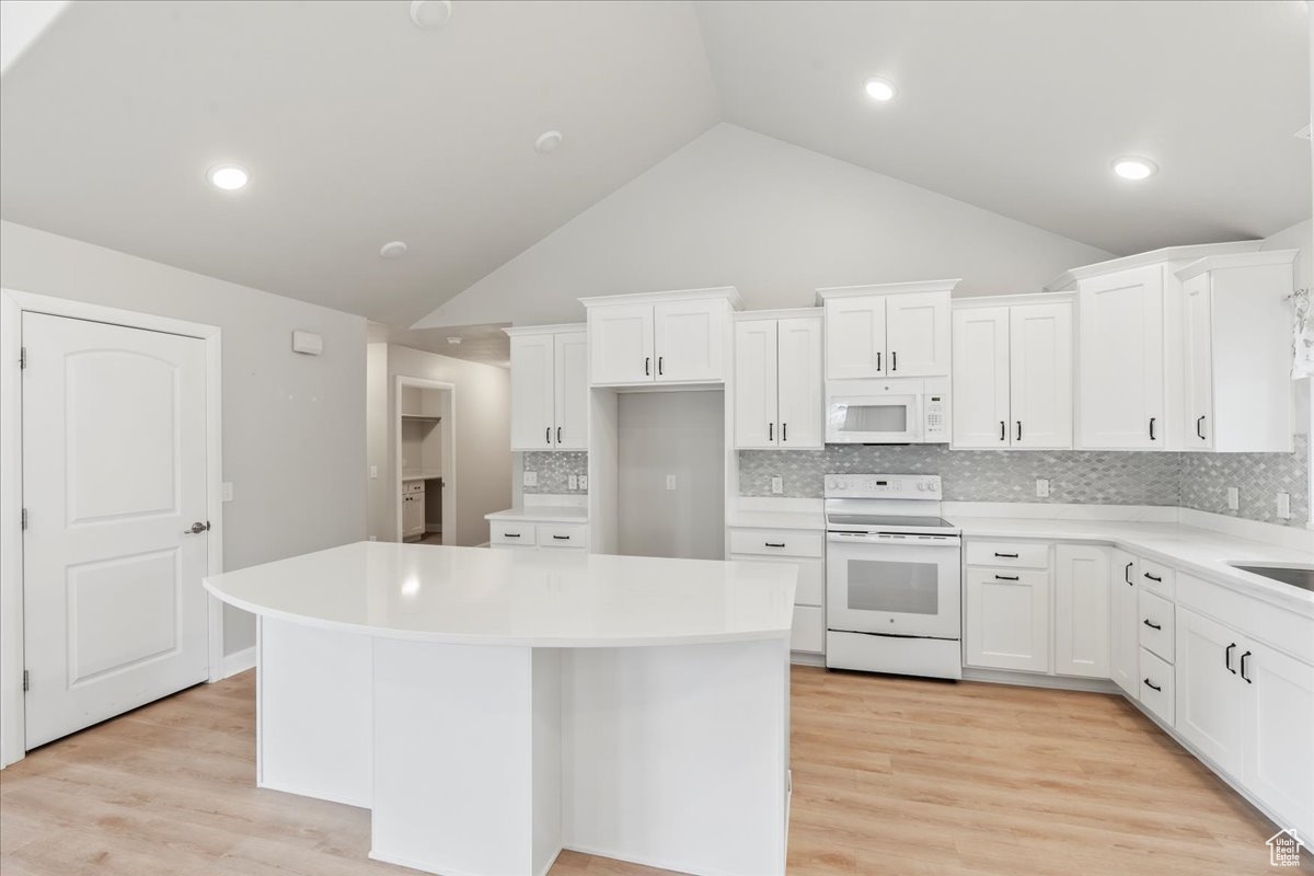 Kitchen featuring white cabinetry, white appliances, and a center island