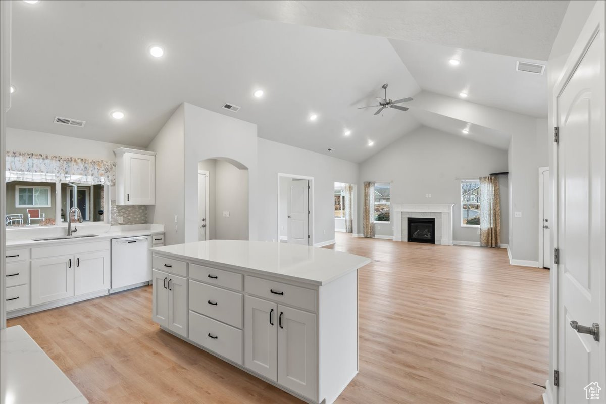 Kitchen featuring sink, white dishwasher, a kitchen island, ceiling fan, and white cabinets