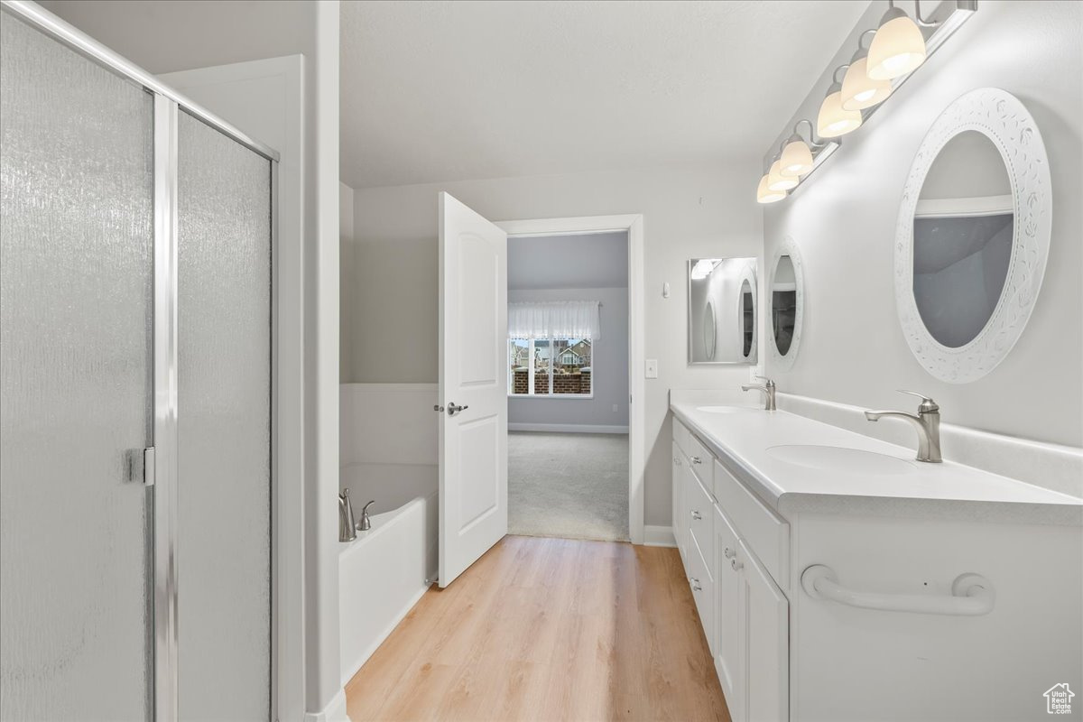 Bathroom with plus walk in shower, hardwood / wood-style floors, and vanity