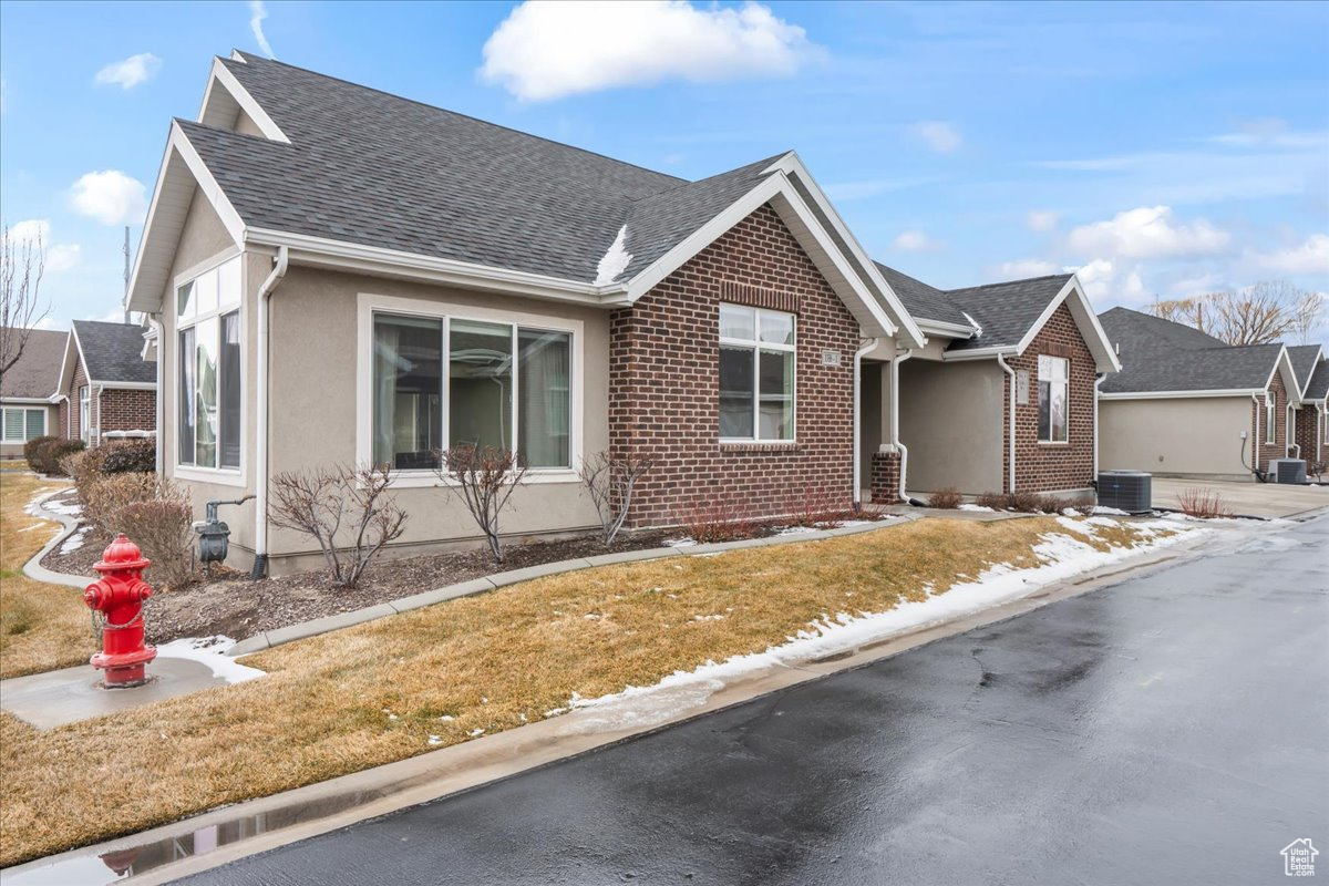 View of front of house with a front yard and central AC unit