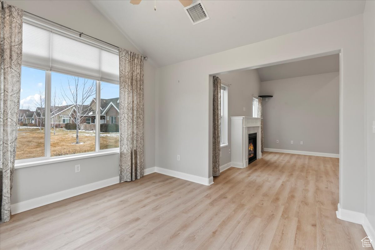 Unfurnished living room with lofted ceiling, ceiling fan, and light hardwood / wood-style flooring