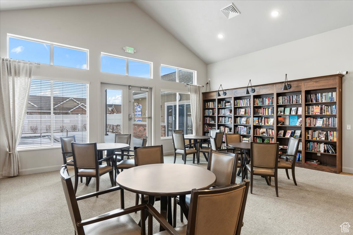 Dining space featuring carpet, plenty of natural light, and high vaulted ceiling