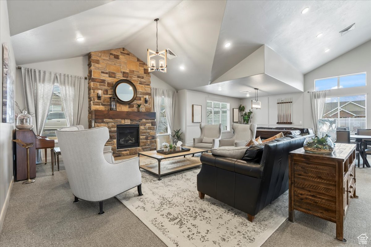 Carpeted living room featuring a stone fireplace, plenty of natural light, and high vaulted ceiling