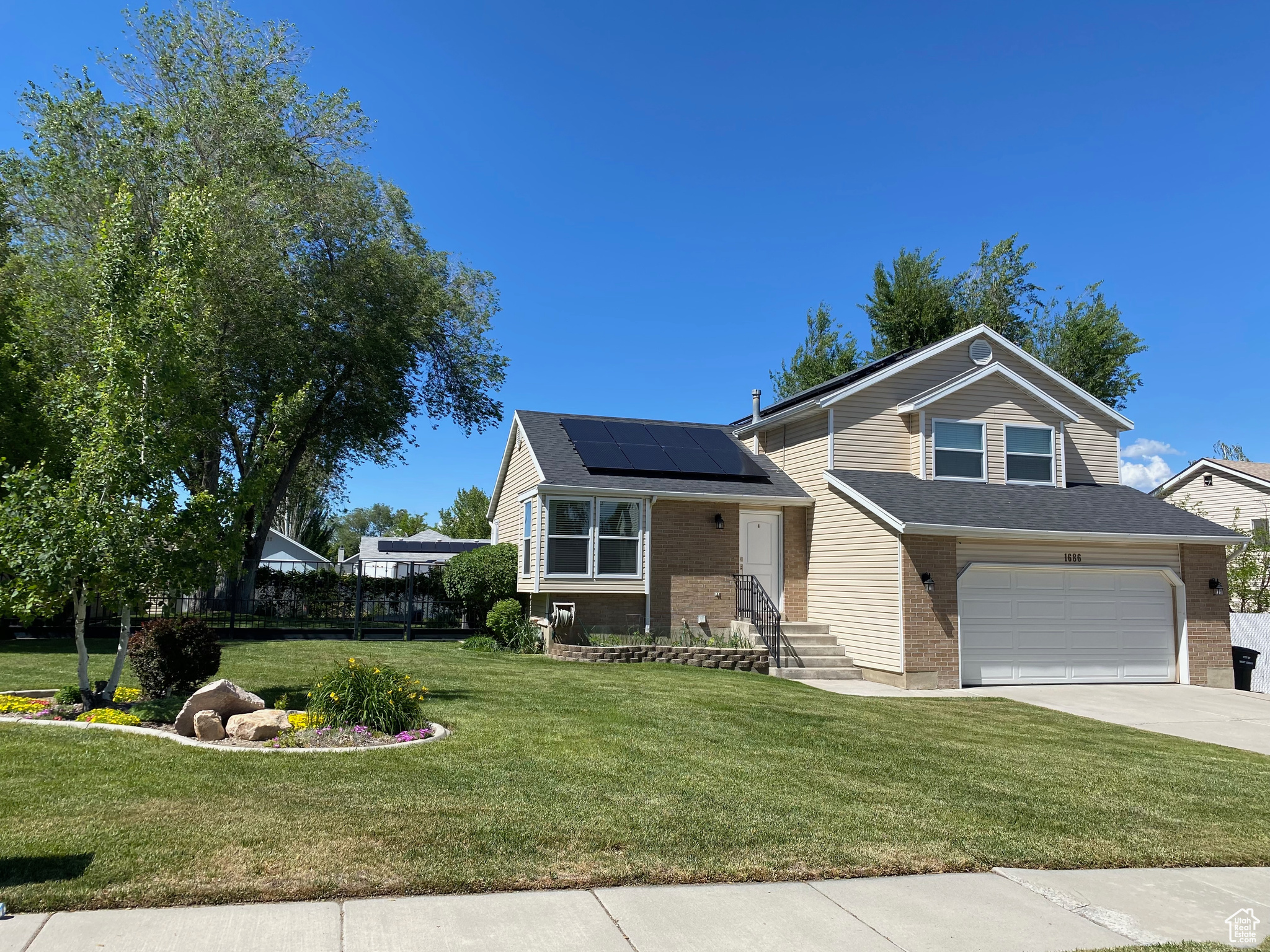 View of front of house featuring a garage, a front yard, and solar panels