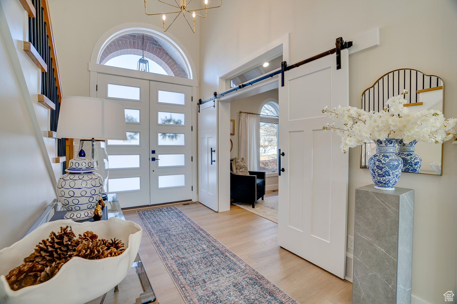 Entrance foyer featuring a high ceiling, a barn door, a chandelier, and light hardwood / wood-style floors