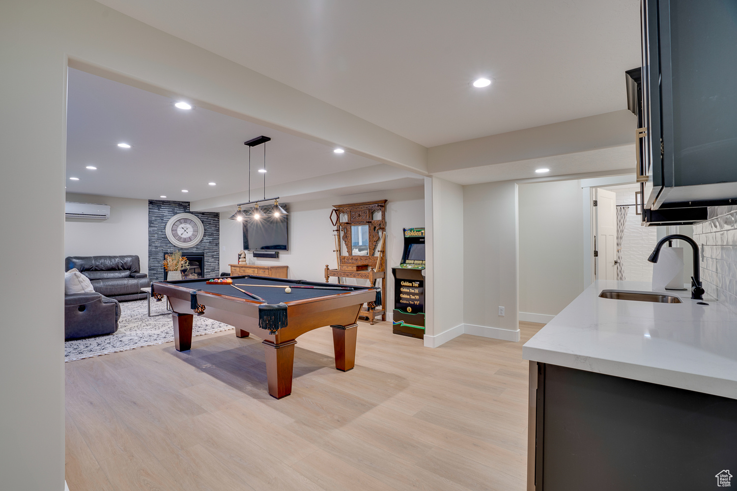 Playroom featuring an AC wall unit, a fireplace, billiards, sink, and light hardwood / wood-style floors