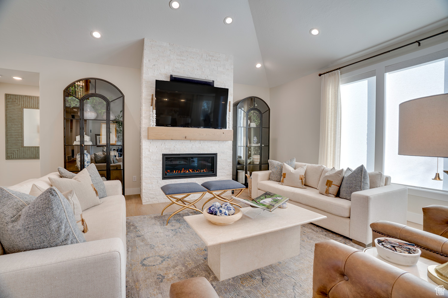 Living room featuring a stone fireplace, vaulted ceiling, and light wood-type flooring