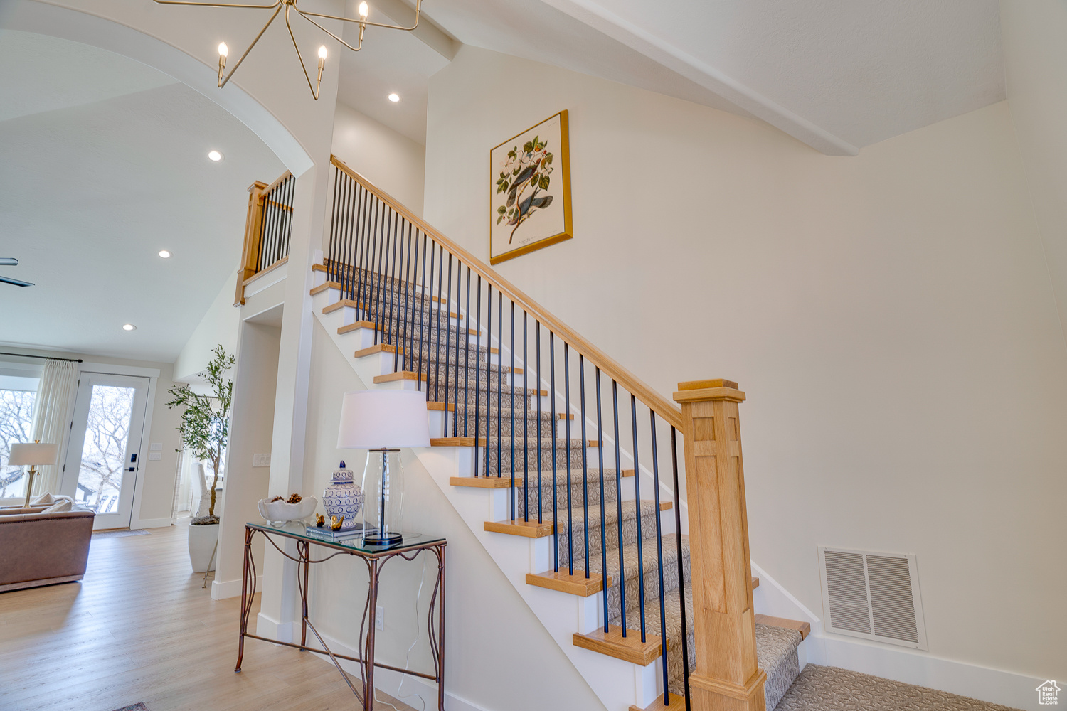 Staircase with wood-type flooring, a chandelier, and high vaulted ceiling