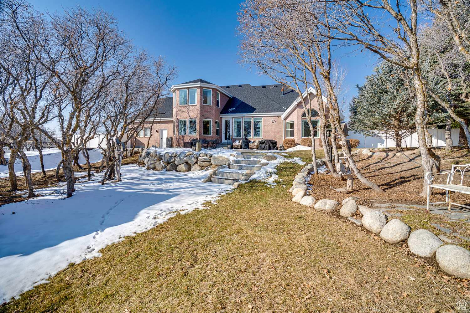 Snow covered back of property with a yard