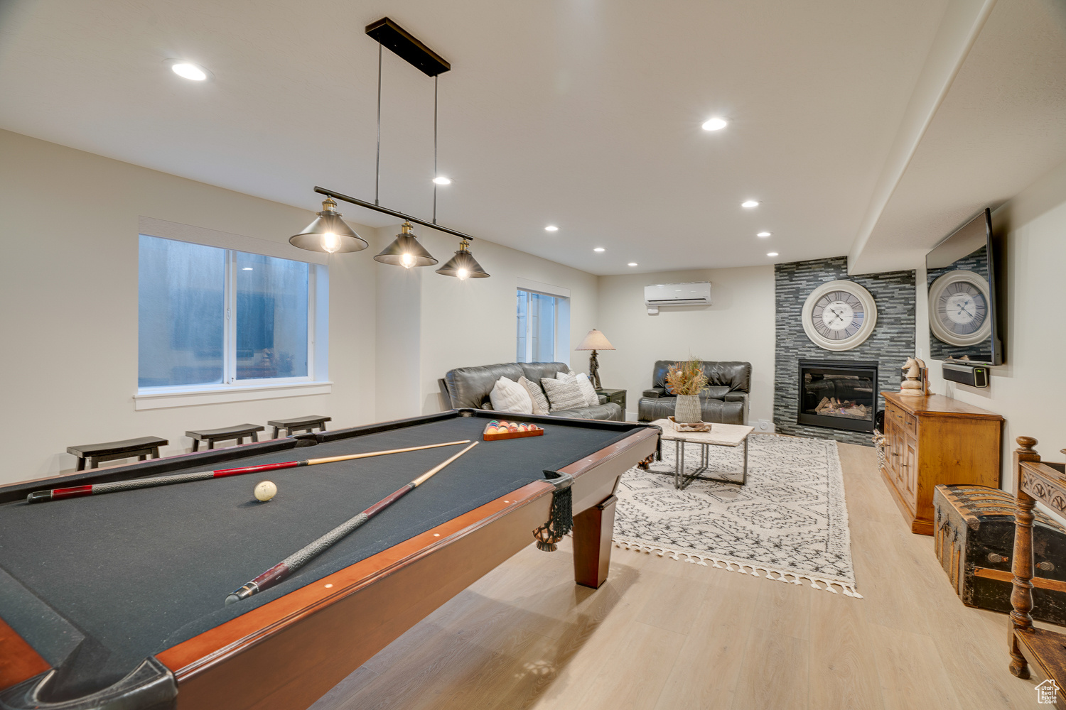 Playroom featuring a wall unit AC, light hardwood / wood-style floors, and a tile fireplace