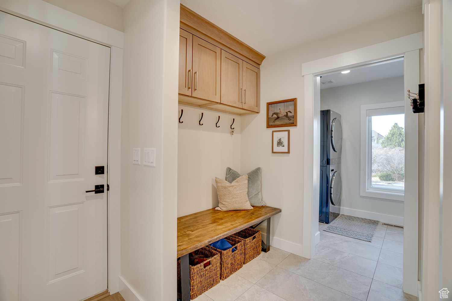 Mudroom featuring light tile patterned flooring and stacked washer / dryer