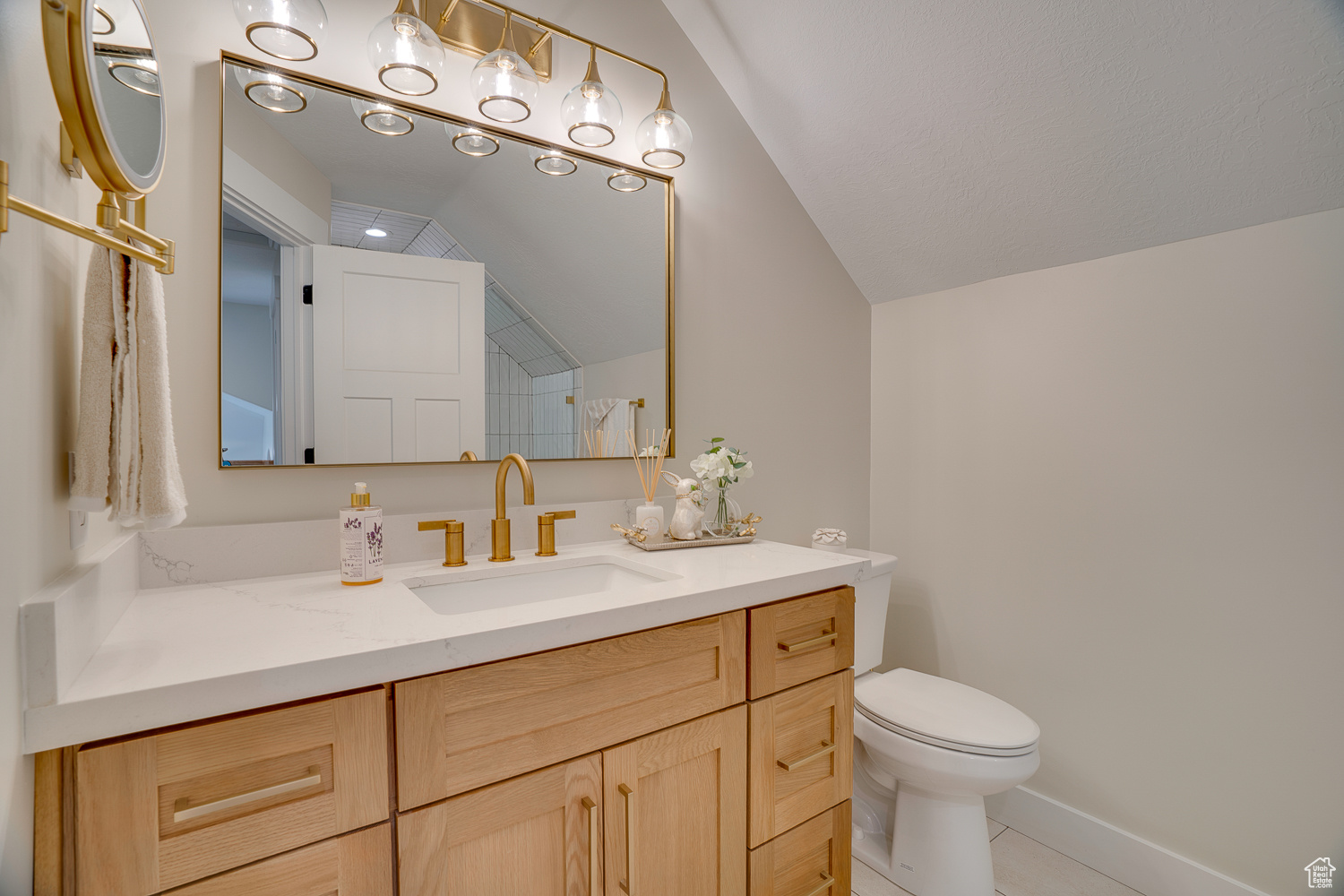 Bathroom featuring lofted ceiling, toilet, tile patterned flooring, and vanity