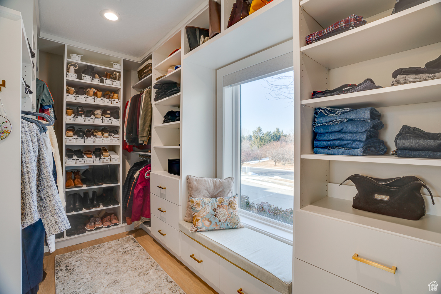 Walk in closet with light hardwood / wood-style floors