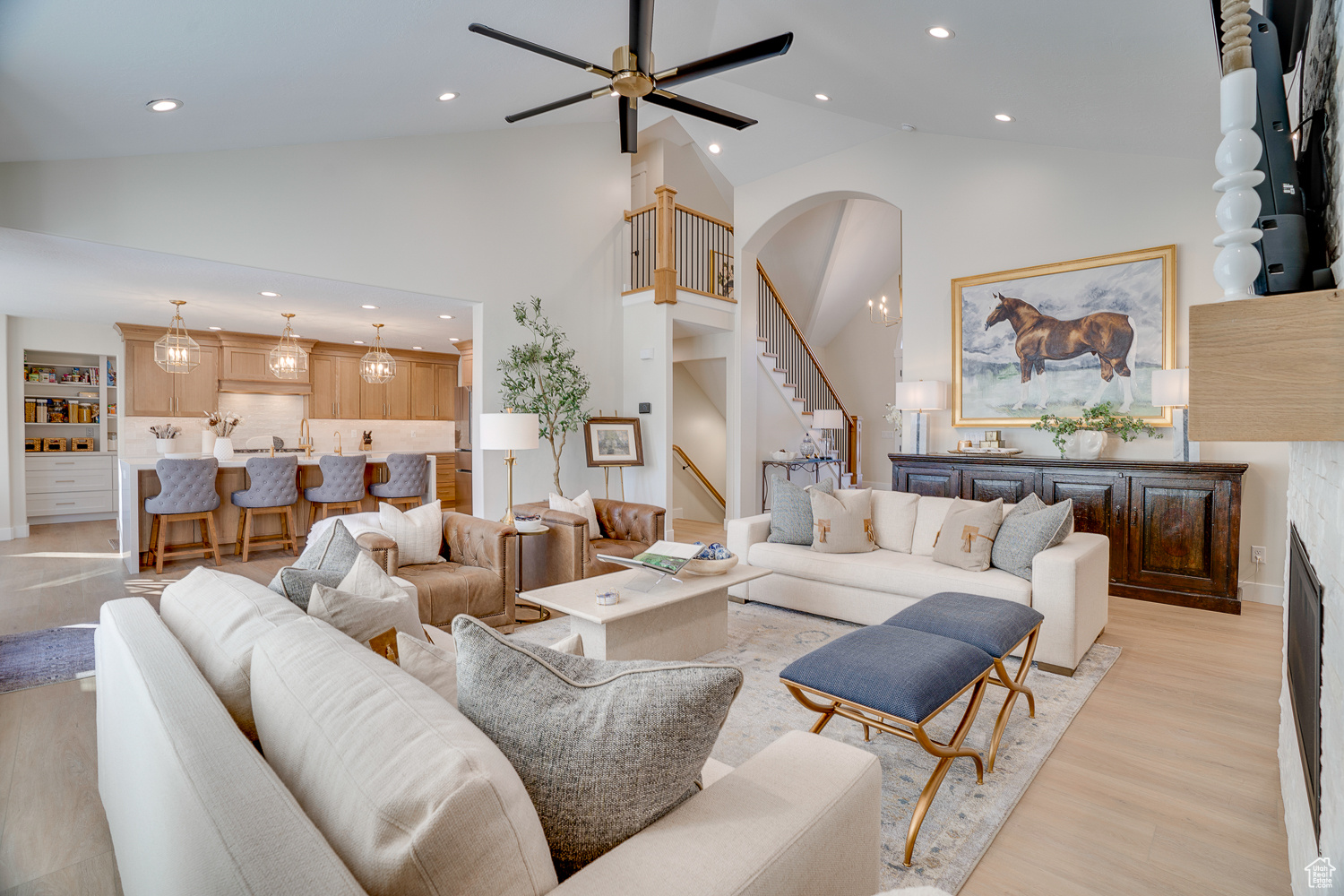 Living room with high vaulted ceiling, ceiling fan, and light hardwood / wood-style flooring