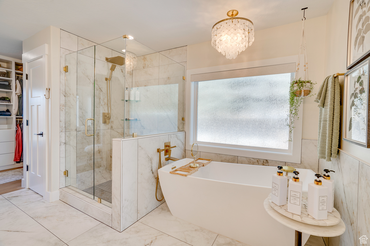 Bathroom with an inviting chandelier, shower with separate bathtub, and tile walls