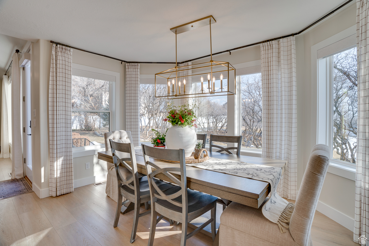 Dining room featuring a healthy amount of sunlight, a notable chandelier, and light hardwood / wood-style flooring