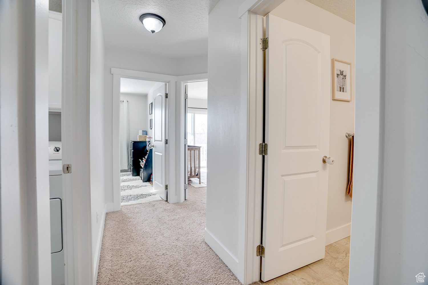 Corridor with light carpet and a textured ceiling