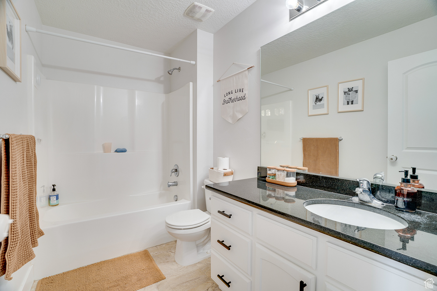 Full bathroom featuring tile patterned floors, toilet, a textured ceiling, shower / tub combination, and vanity