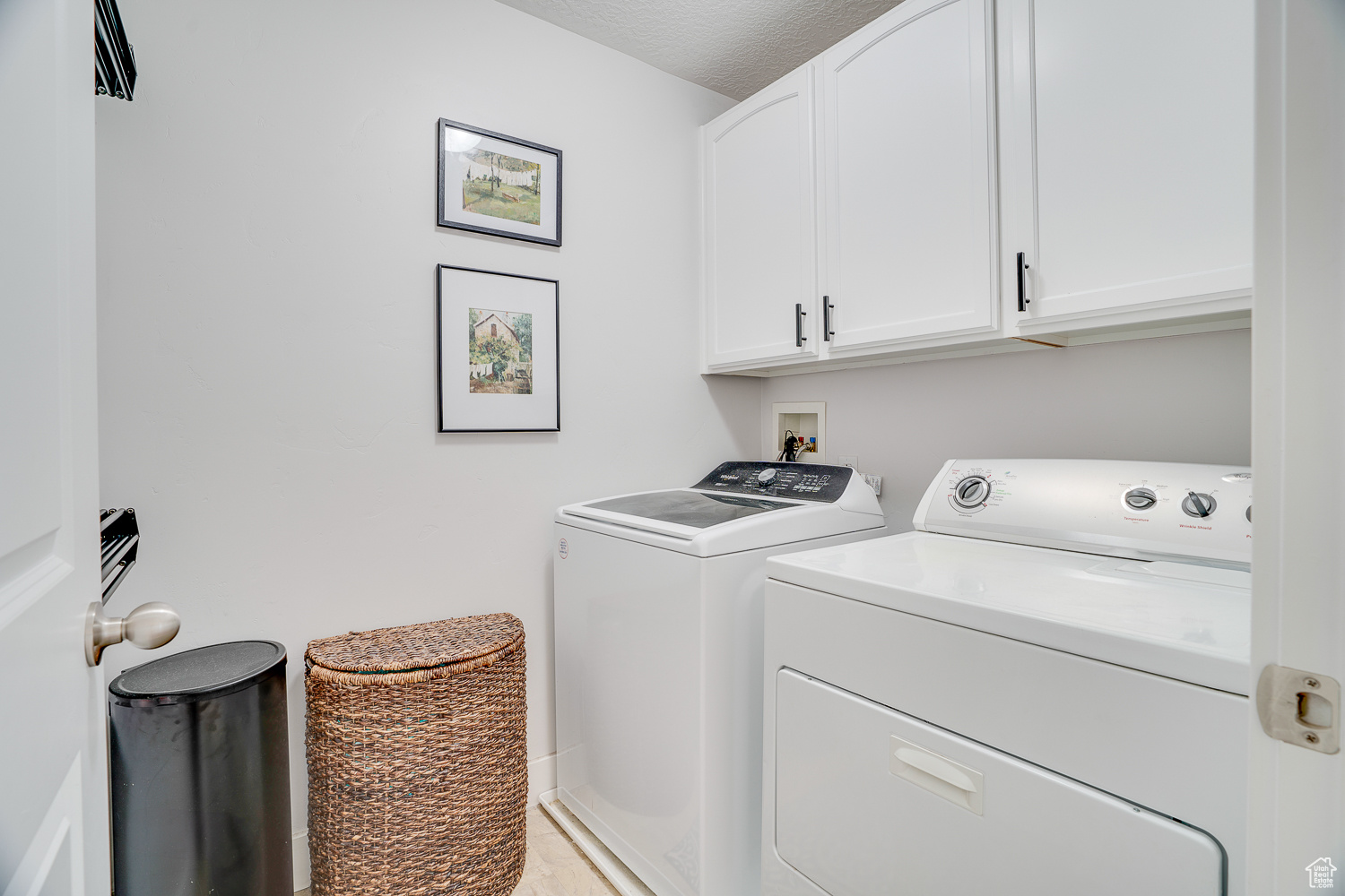 Clothes washing area with cabinets, a textured ceiling, and independent washer and dryer