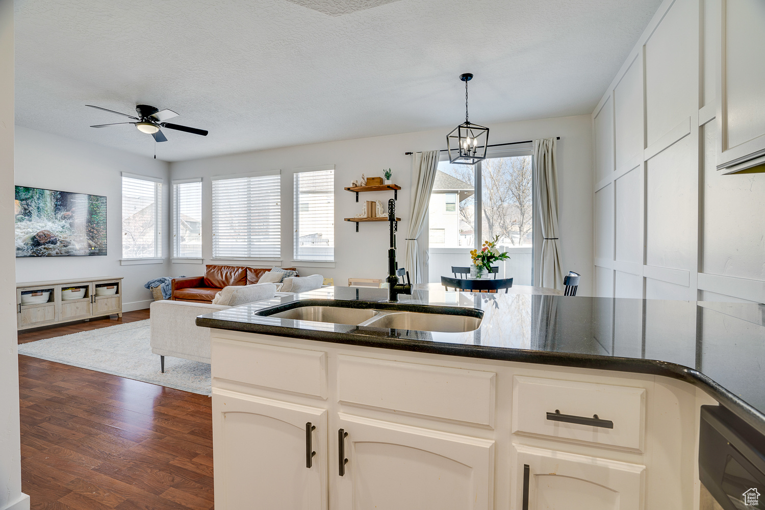 Kitchen featuring white cabinetry, dark hardwood / wood-style flooring, ceiling fan with notable chandelier, and sink