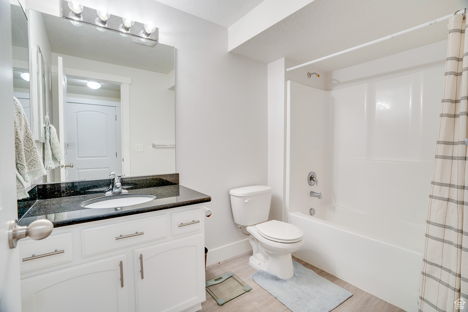 Full bathroom with hardwood / wood-style flooring, vanity, toilet, and shower / tub combo