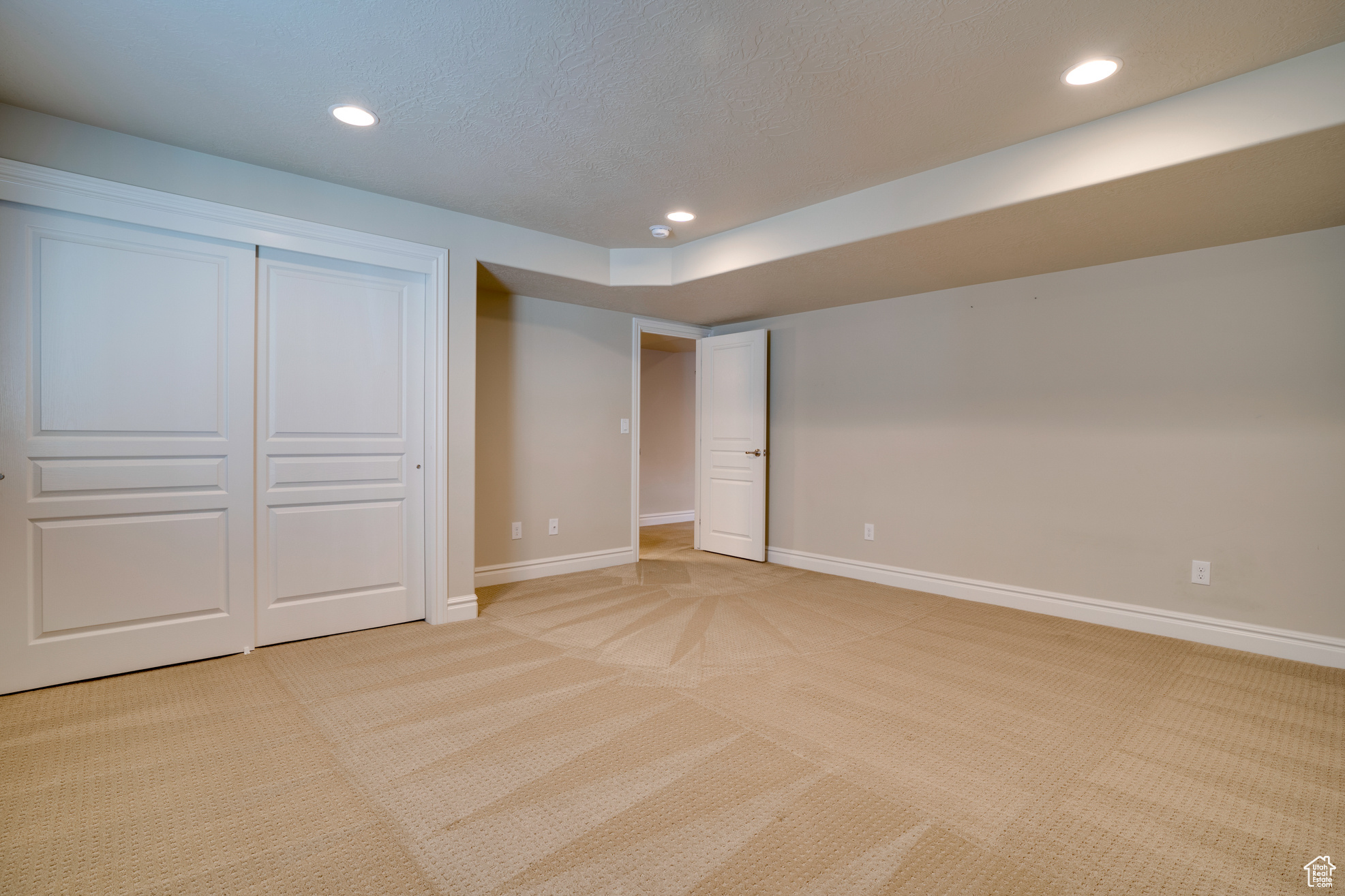 Unfurnished bedroom featuring light colored carpet, a textured ceiling, and a closet