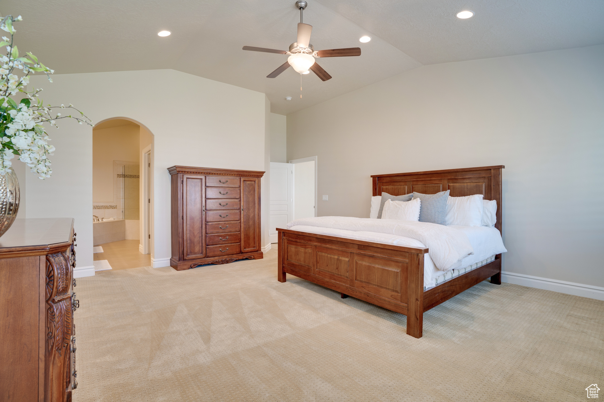 Carpeted bedroom featuring ensuite bath, vaulted ceiling, and ceiling fan