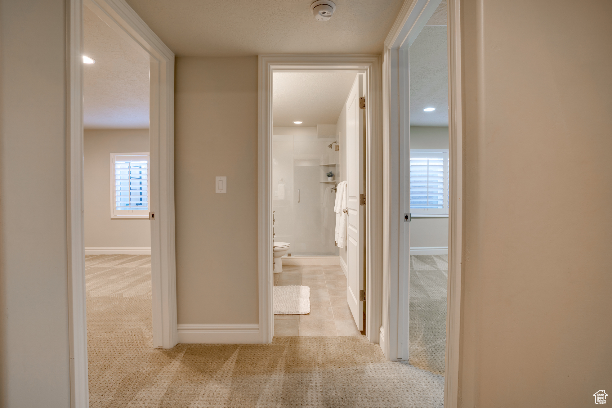 Corridor featuring light colored carpet