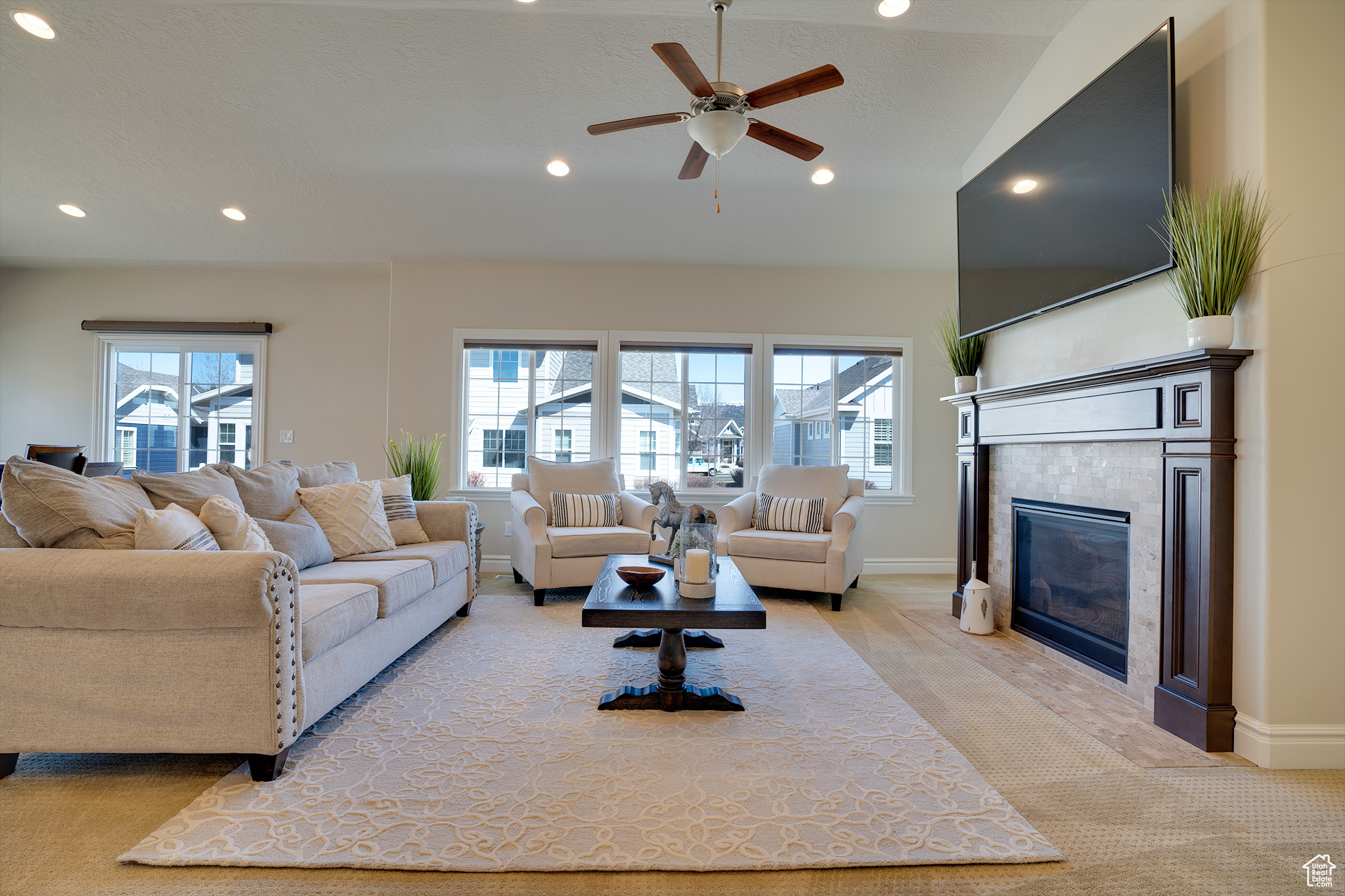 Living room featuring lofted ceiling, a fireplace, and ceiling fan