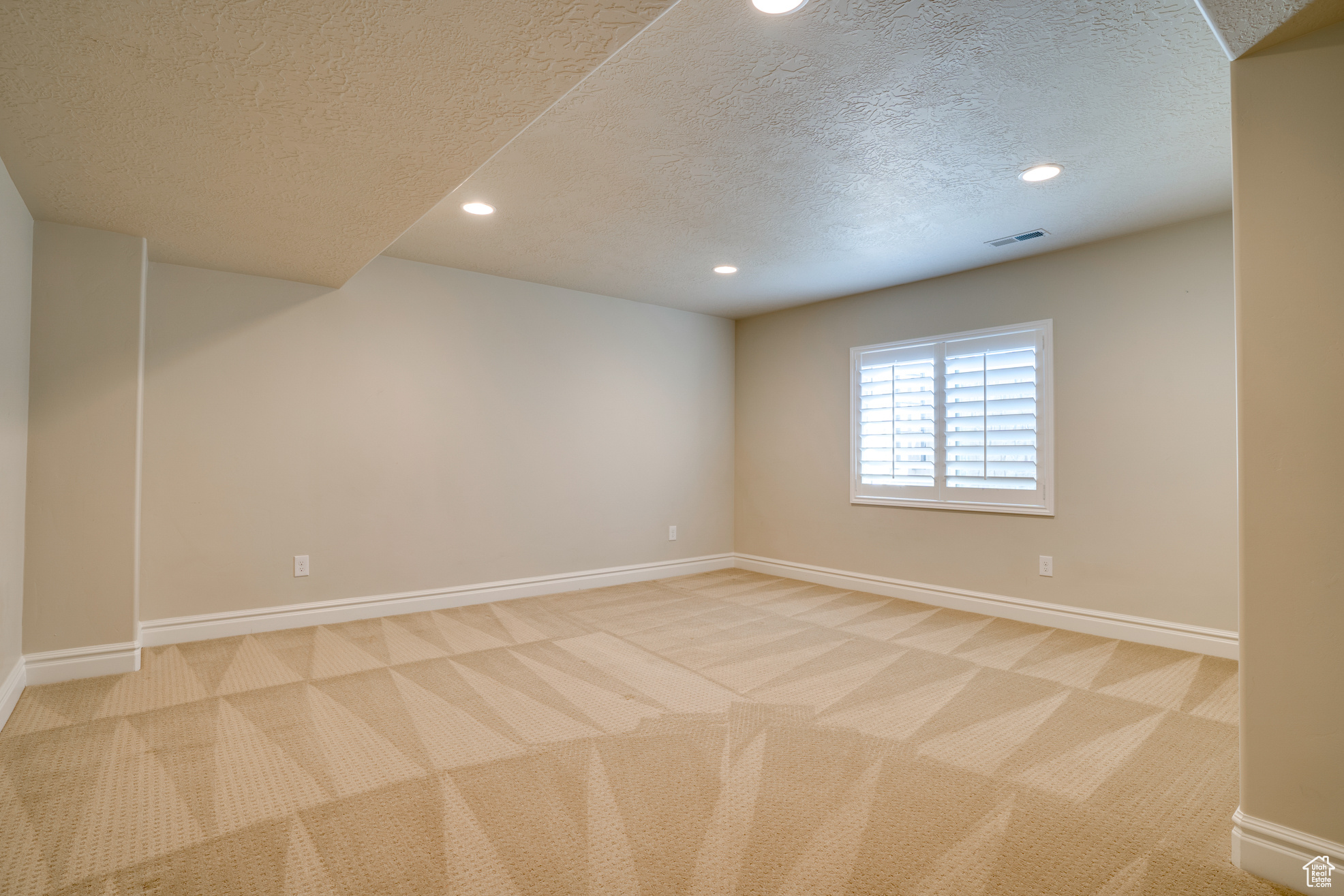 Unfurnished room with light carpet and a textured ceiling