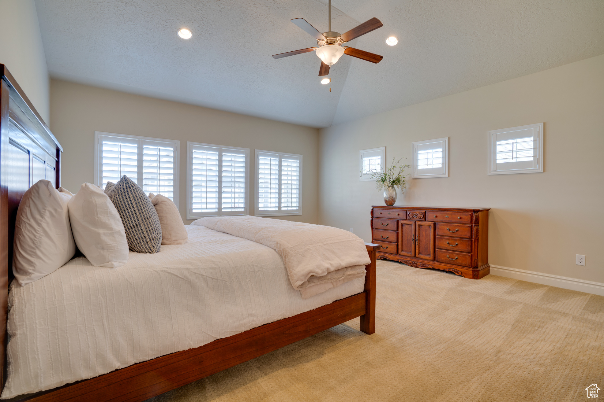 Carpeted bedroom with vaulted ceiling and ceiling fan