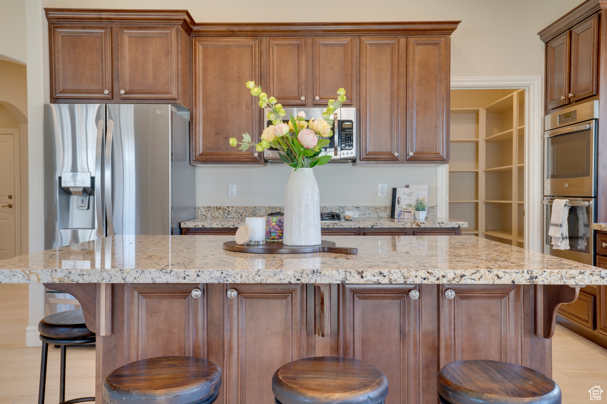 Kitchen with light stone countertops, stainless steel appliances, a center island, and a kitchen bar