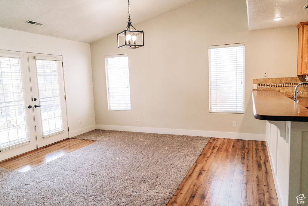 Unfurnished dining area featuring vaulted ceiling, sink, dark hardwood / wood-style flooring, and french doors