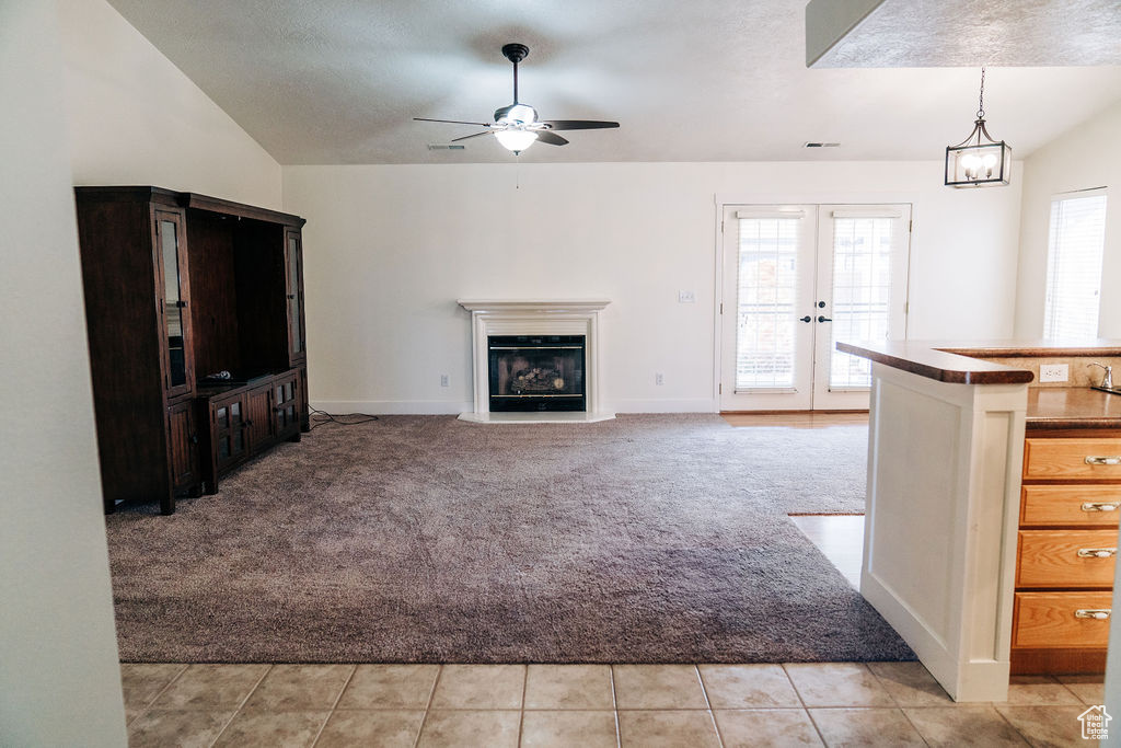 Unfurnished living room with light carpet, lofted ceiling, french doors, and ceiling fan