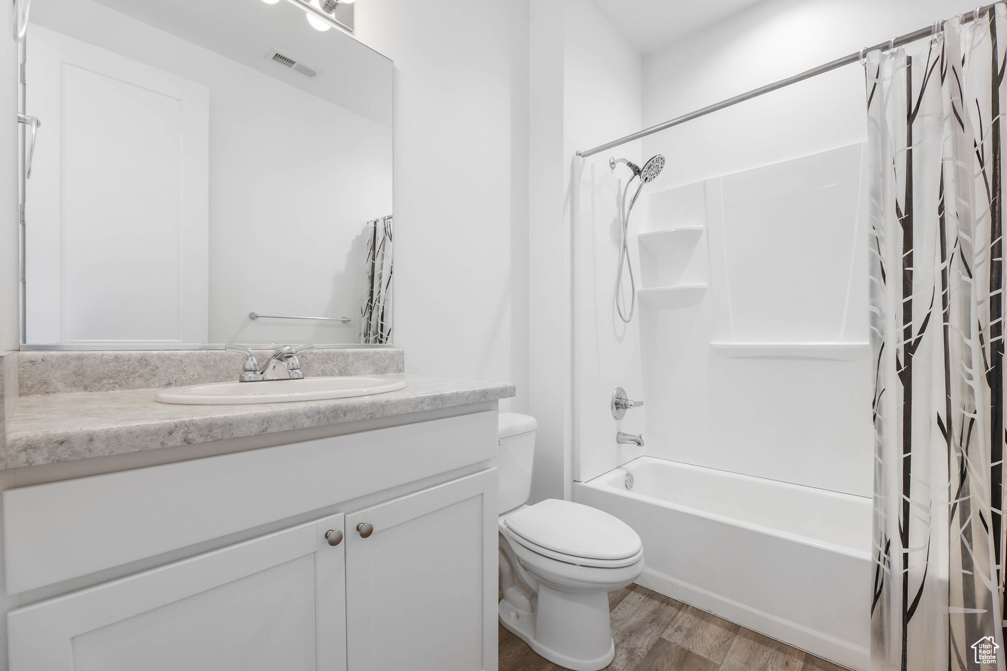 Full bathroom with vanity, hardwood / wood-style flooring, toilet, and shower / bath combo with shower curtain