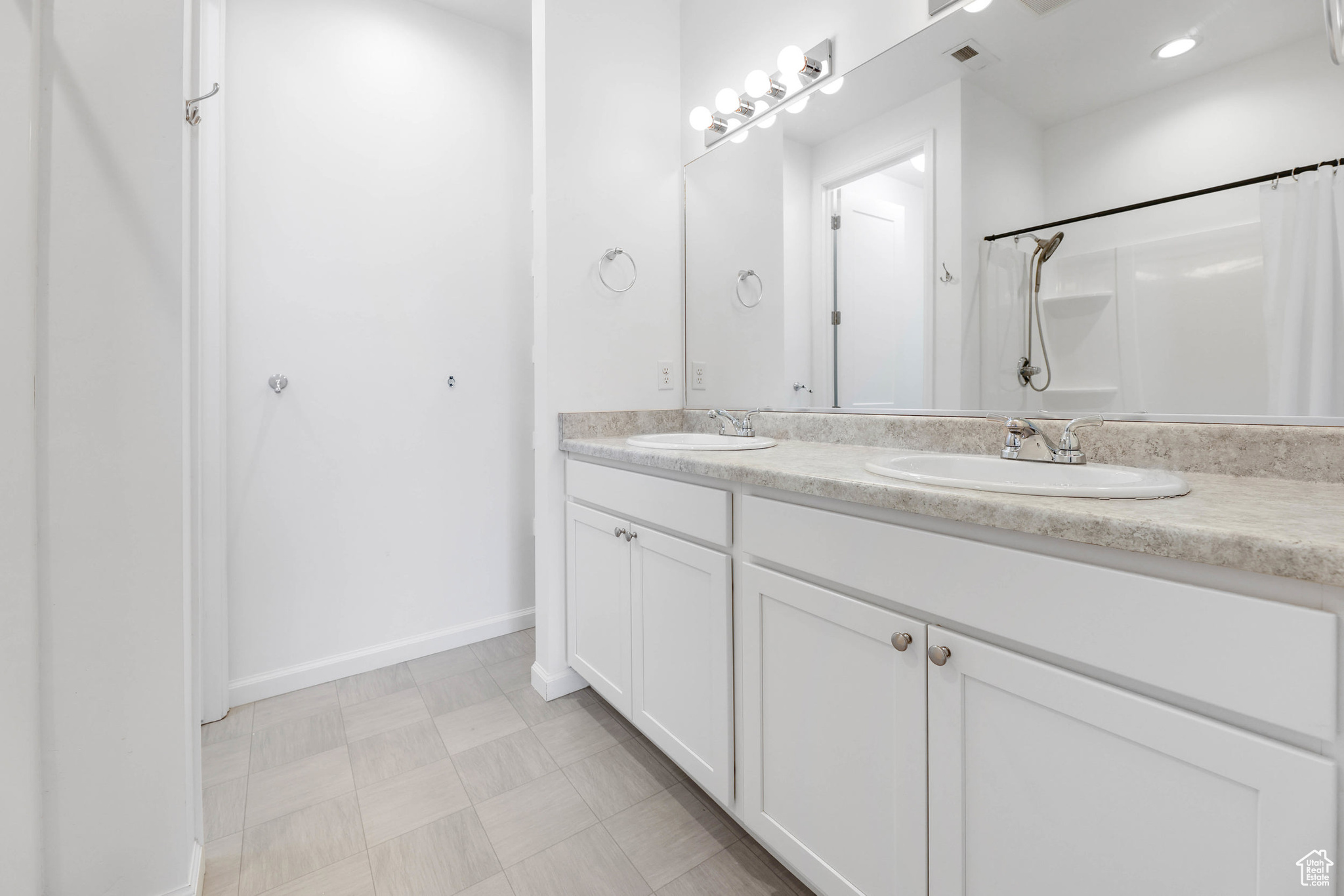 Bathroom featuring double vanity and walk in shower located off the primary bedroom.