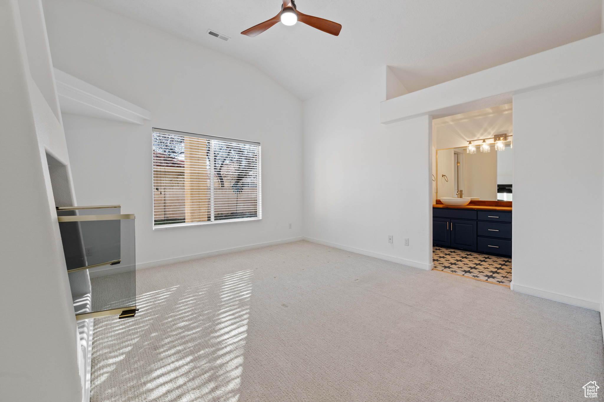 Unfurnished bedroom with sink, ceiling fan, connected bathroom, vaulted ceiling, and light colored carpet