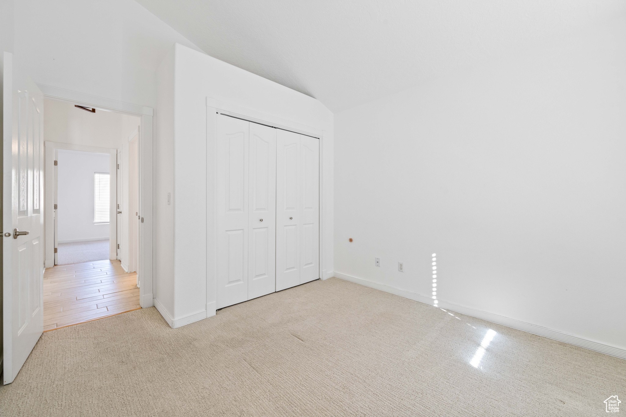 Unfurnished bedroom with light carpet, lofted ceiling, and a closet