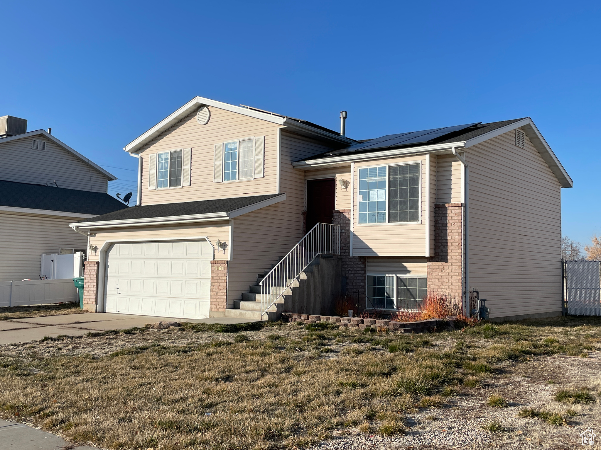 Split level home featuring a garage and solar panels