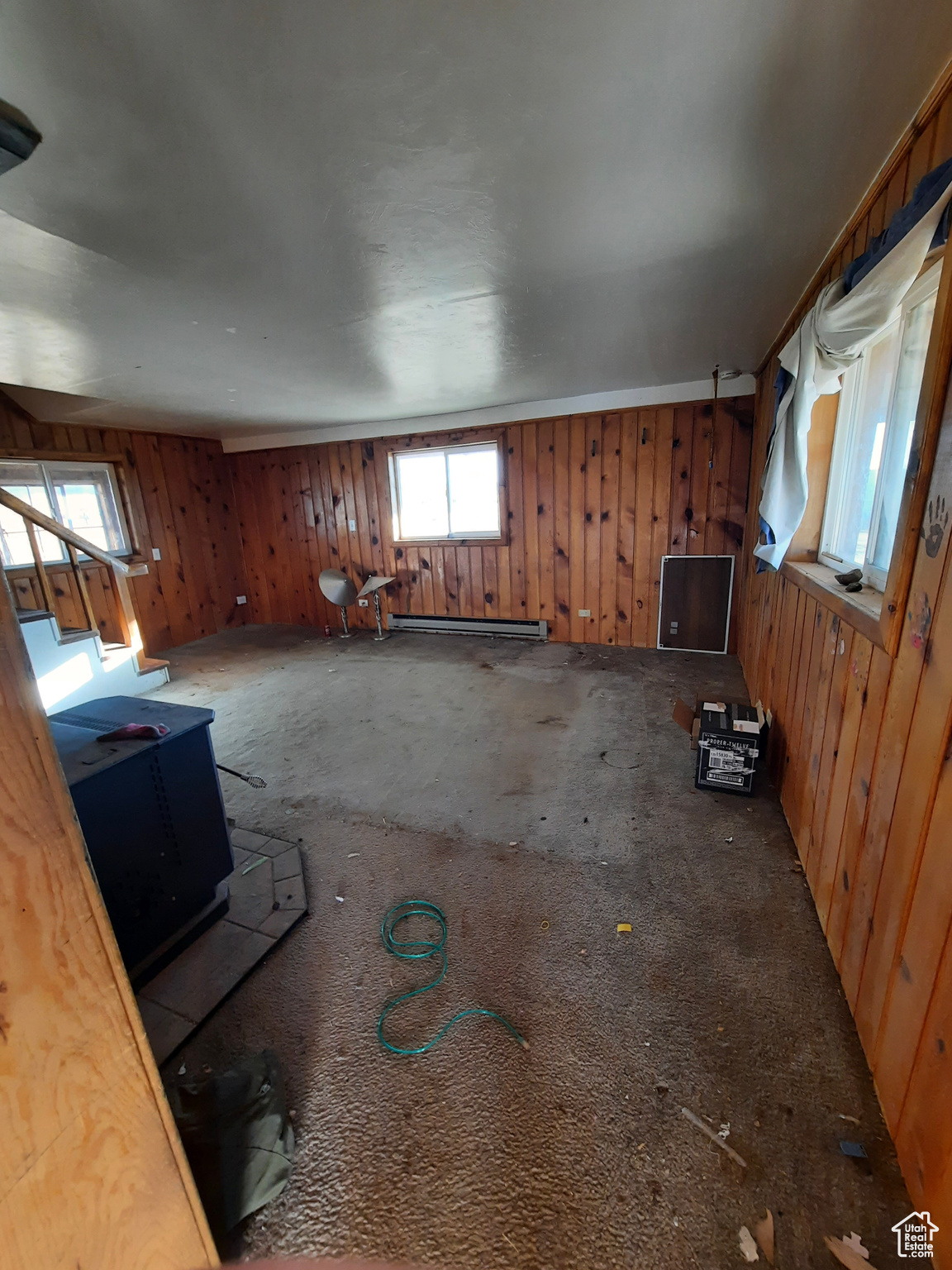 Unfurnished living room with a baseboard heating unit and wood walls