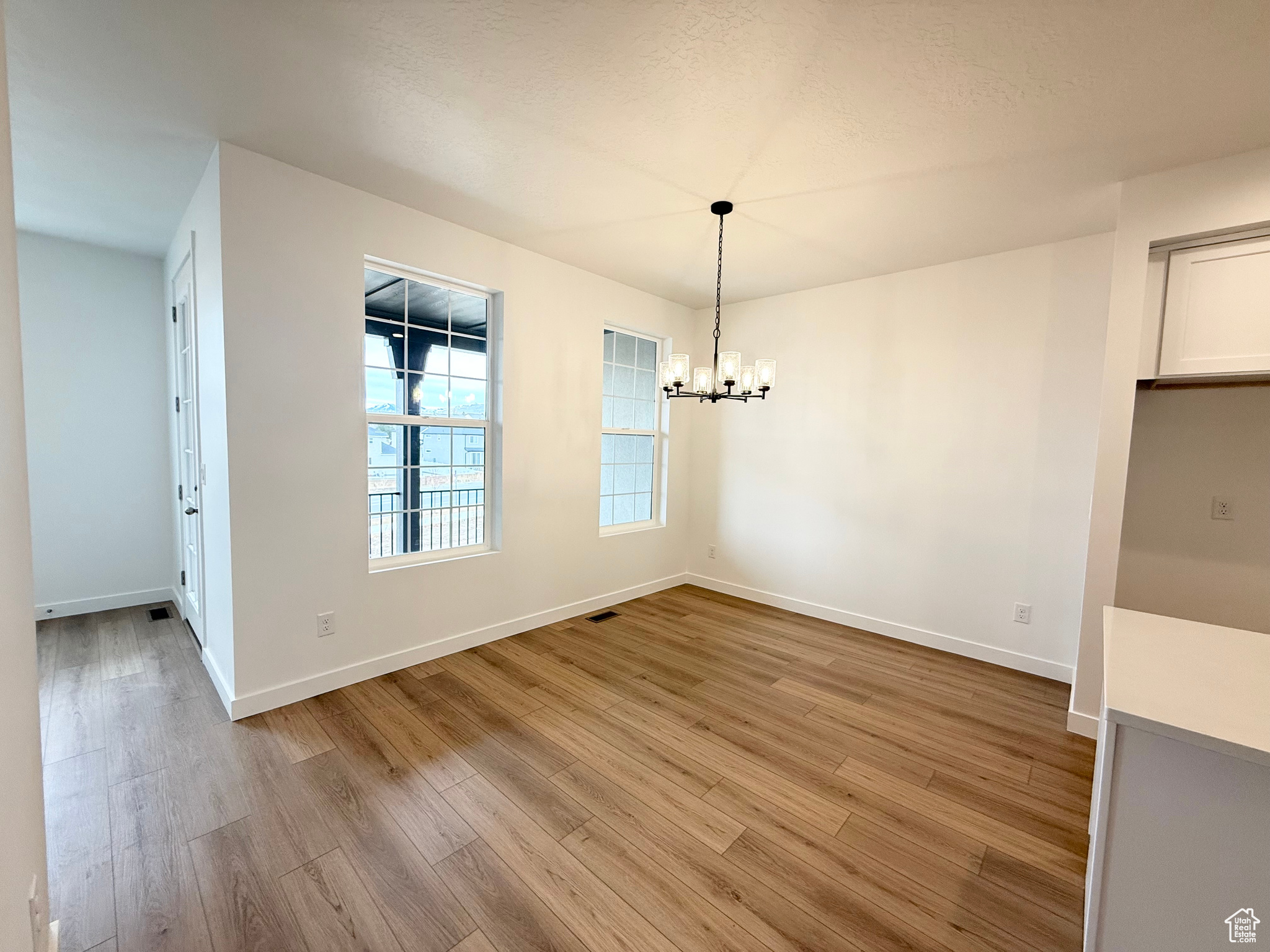 Unfurnished dining area featuring an inviting chandelier and light wood-type flooring