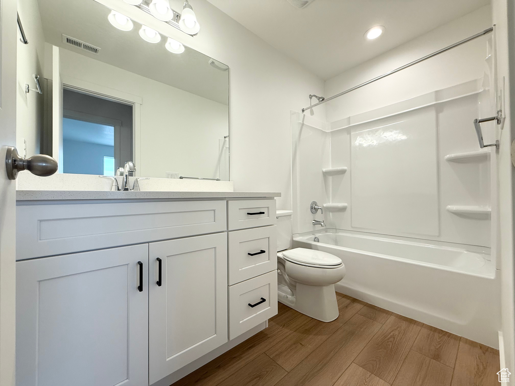 Full bathroom featuring washtub / shower combination, wood-type flooring, toilet, and vanity